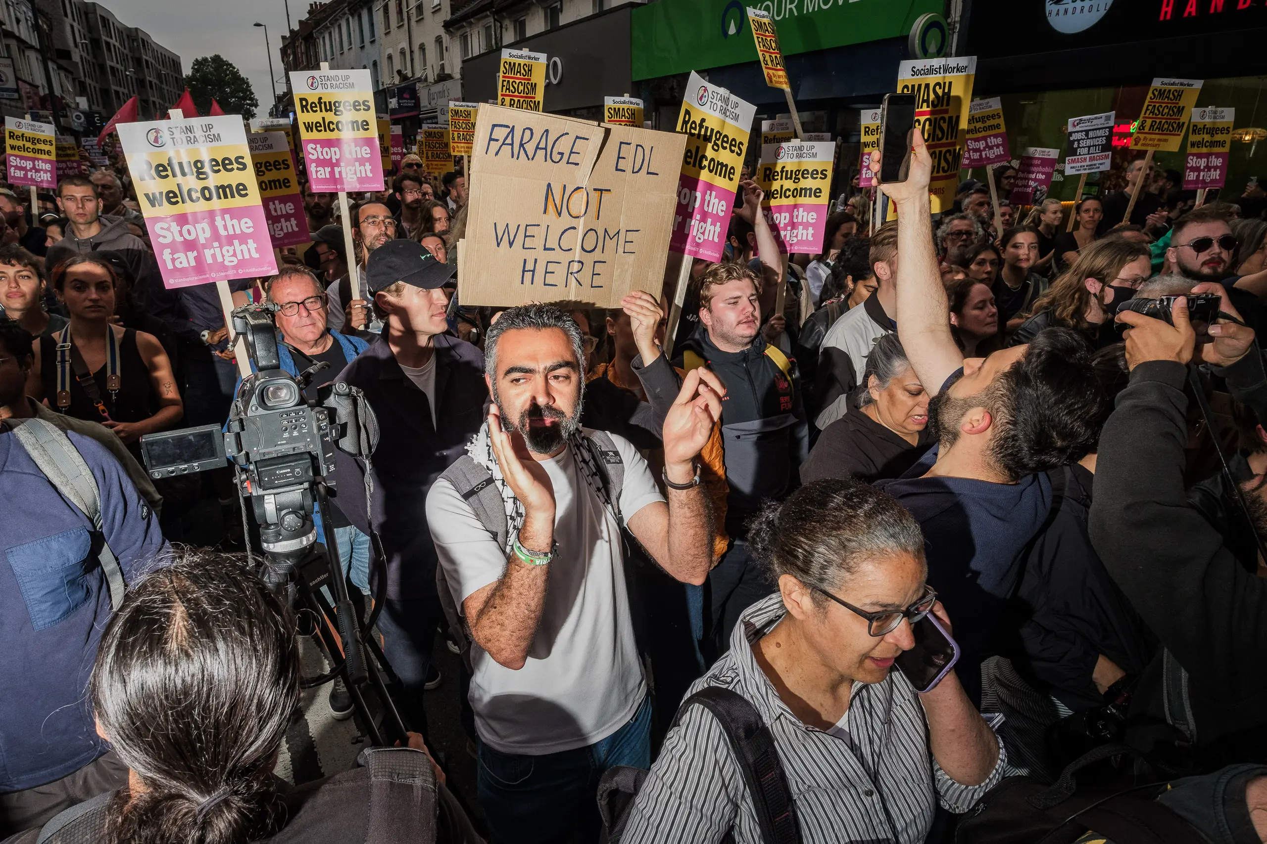 A man holds a sign saying 'Farage EDL not welcome here.' On the night of August 7, 2024 in Walthamstow, North-East London, a gathering of over 10,000 people put paid to a wave of racially motivated riots that had swept the UK for nearly two weeks, targeting Muslims, parts of the asylum system and the police. Similar anti-racist protests happened in Birmingham, Brentford, Brighton, Bristol, Newcastle and North Finchley.